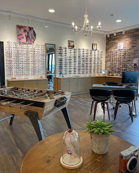 L'intérieur de la boutique : murs de montures, babyfoot et bureau de conseil